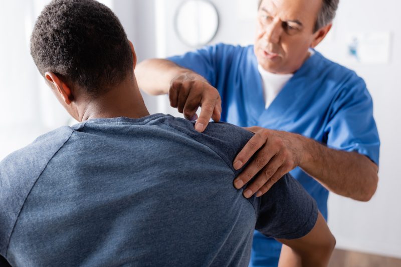 blurred therapist working with african american man in clinic